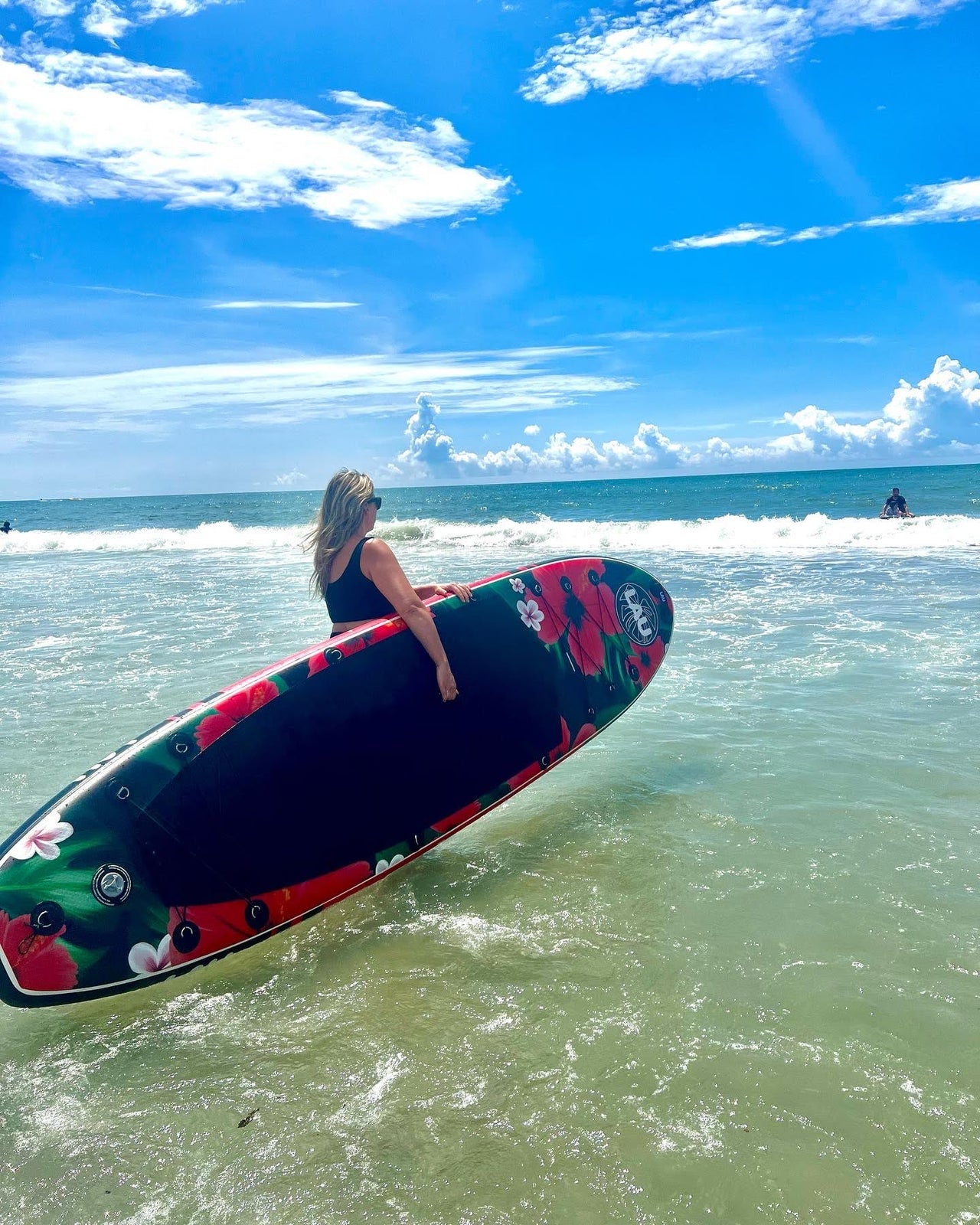 femme aux cheveux blonds tenant un paddle board gonflable lau sup dans la mer