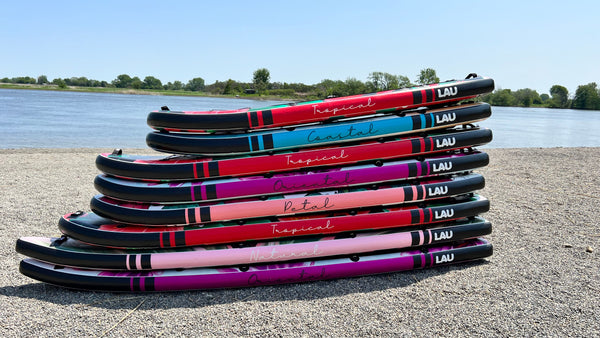 8 paddle boards gonflables lau sup empilés sur une plage